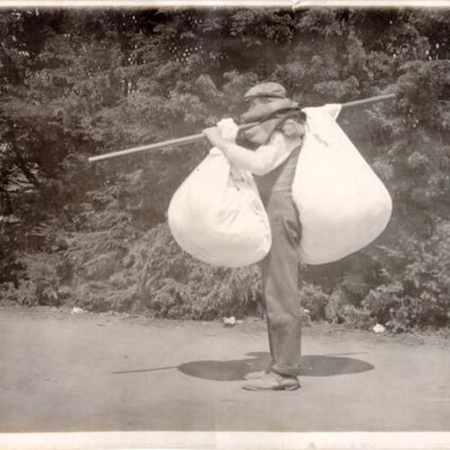 [Refugee carrying his possessions in two large bags]