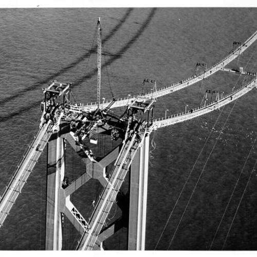 [Aerial view of men on catwalks and cable saddles on top of San Francisco-Oakland Bay Bridge tower during construction]