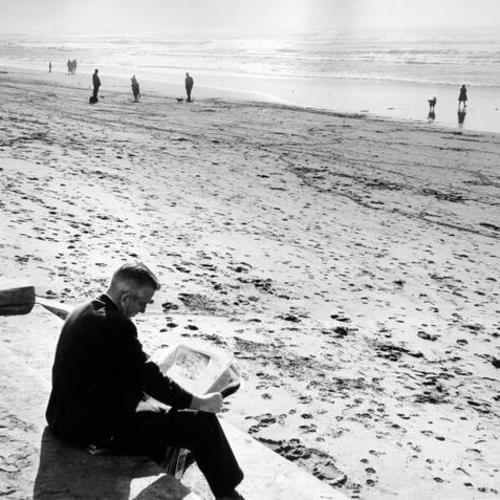[Man reading a newspaper at Ocean Beach]
