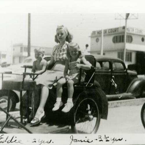 [Jane with her mother Mary and brother Eddie sitting on a pedi-cab built by her father on Wawona Street]