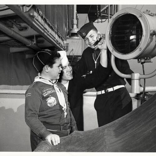 [Seaman John Nelson showing Cub Scout Michael Broock and Explorer Scout Al Garduno the operation of a signal lamp on the carrier USS Kearsarge]