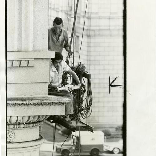 [Leo Moldero and Bill Phelan drilling holes in the granite above the columns on City Hall as part of an effort to keep pigeons off the building]