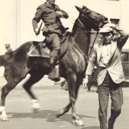 [Police officer on horse driving back man during strike]