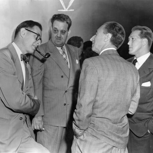 [Harry Bridges faces away from the camera as he talks with his attorney during recess today in hearing on revocation of his bail (from left) are Norman Leonard, William F. Cleary and James M. MacInnis]
