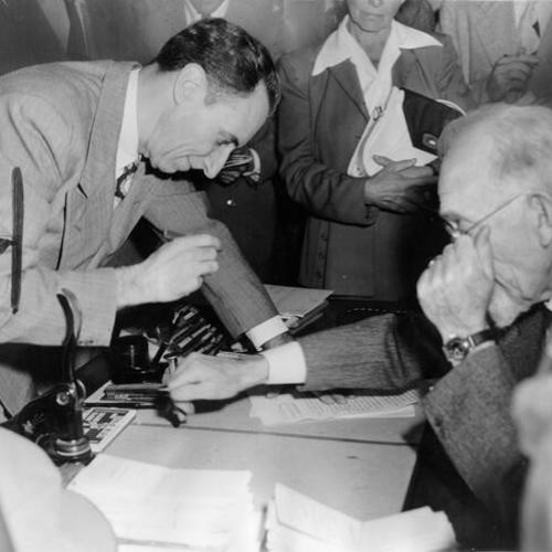 [Labor leader Harry Bridges is shown as he prepares to sign formal documents relating to his bail on being released from federal custody]