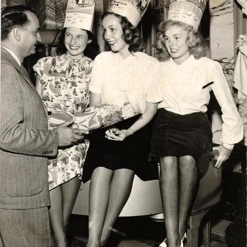 [Three women, Mauricette Du Frony, Joy Groom and Sandy Day, being crowned "Miss Cable Car of 1947" by Winston Churchill Black]