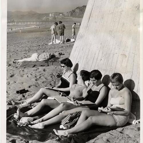 [Four young women sunbathing and studying at Ocean Beach]