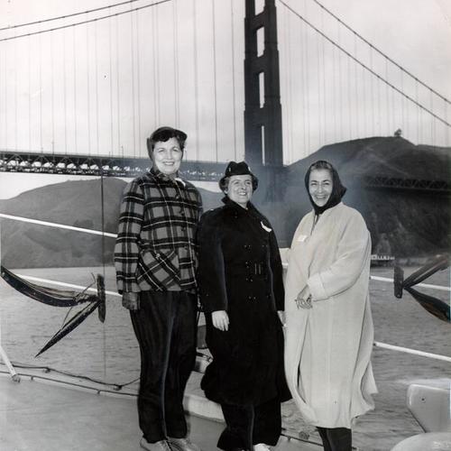 [Mrs. Carma Zimmerman, Lt. J. G. Barbara Sullivan, USN, and Mrs. Robert M. Levison passing underneath the Golden Gate Bridge on a Navy destroyer escort]