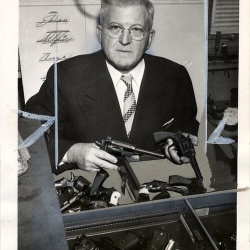 [Francis X. Latulipe, Jr. holding two guns in his workshop]