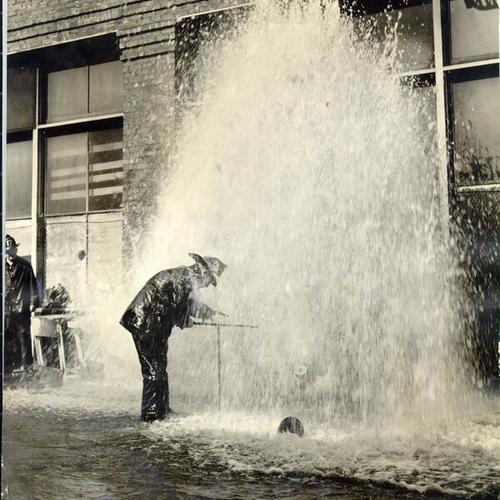 [Fireman John Flanagan trying to shut off a broken water hydrant on Minna Street]