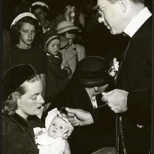 [Father John Kane bestowing blessing on six week old Maureen Lockhart at St. Anne's Church]