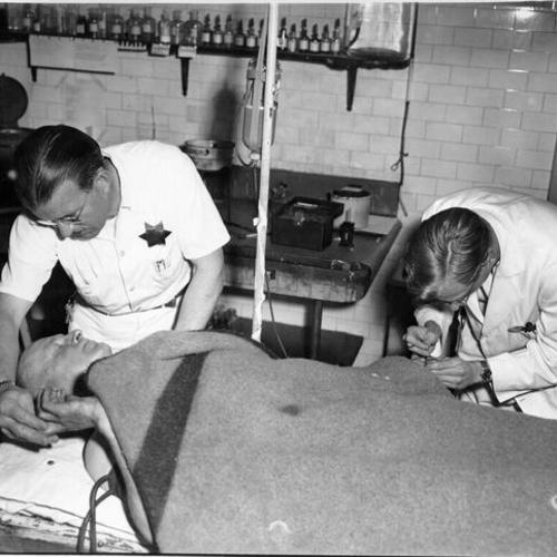 [Steward Pat Brown and Frank Segal helping a patient at Mission Emergency Hospital]