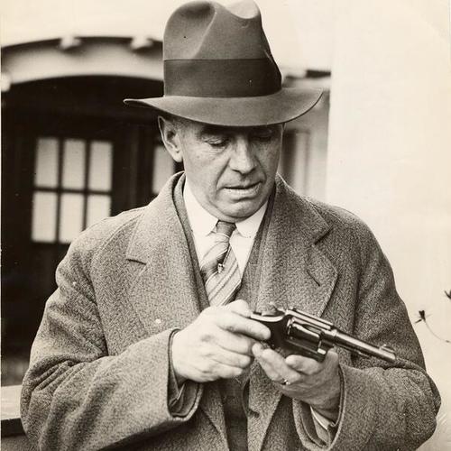 [Detective Sergeant E.J. McSheehy inspecting the gun used in a double killing]