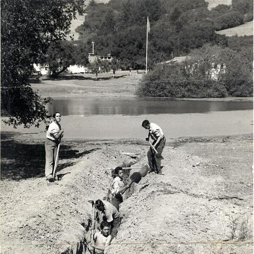[Director of Log Cabin Ranch Jack Adams and boys making a swimming pool out of a lake]