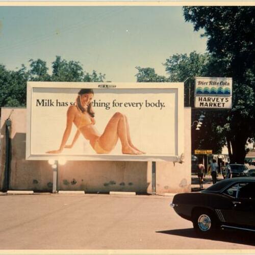 ["Milk has something for every body" billboard next to "Harvey's Market" grocery store]