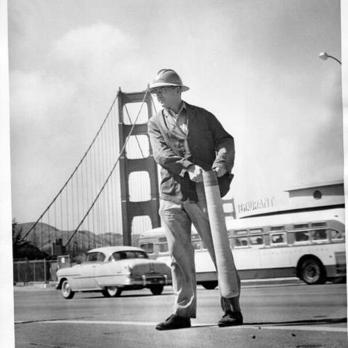 [Workman moving traffic control marker on Golden Gate Bridge]