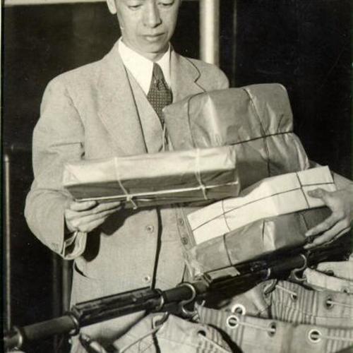 [Ju S. Kim, in charge of the Chinatown Post Office, sorting mail]