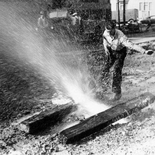 [Frank O'Neil stopping a flood of water gushing from a broken water main on Jackson Street near Divisadero]