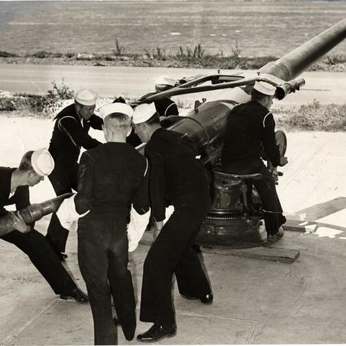 [Members of gun crew loading 100-pound shells]