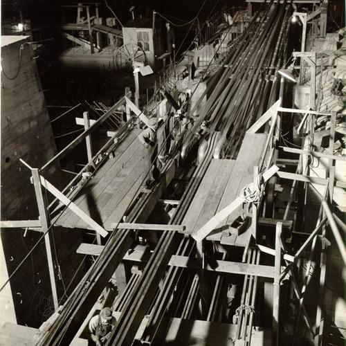 [Workers spinning cables at night during construction of the San Francisco-Oakland Bay Bridge]