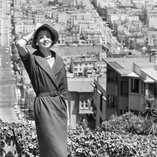 [Woman posing for a photograph at the top of Lombard Street, with Telegraph Hill in background]