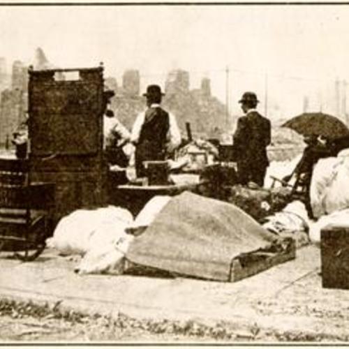 [Refugees on a street corner with salvaged goods]