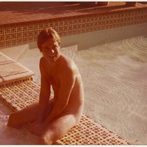 Armistead Maupin, nude, sitting on edge of swimming pool at Rock Hudson's home, The Castle, Beverly Hills
