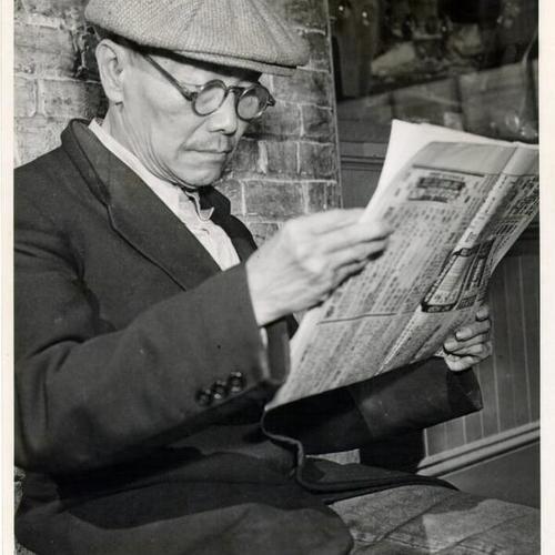 [Chan Ching reading a Chinese newspaper]