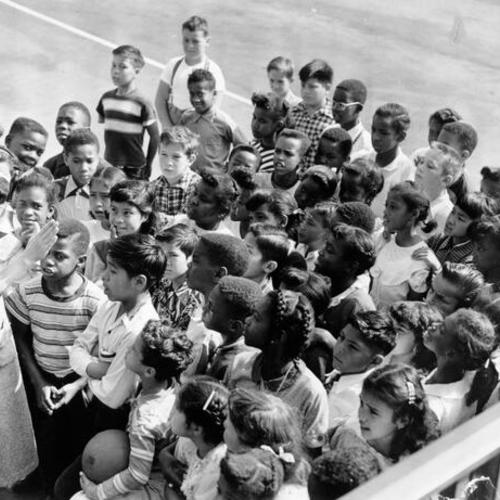 [Teacher Lucille Heath with a group of children in the playground of Bessie Carmichael School]