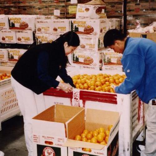 [Annice and Joseph sorting oranges into smaller boxes at the San Francisco Food Bank]