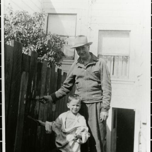 [Charles and his father James, painting their backyard fence]