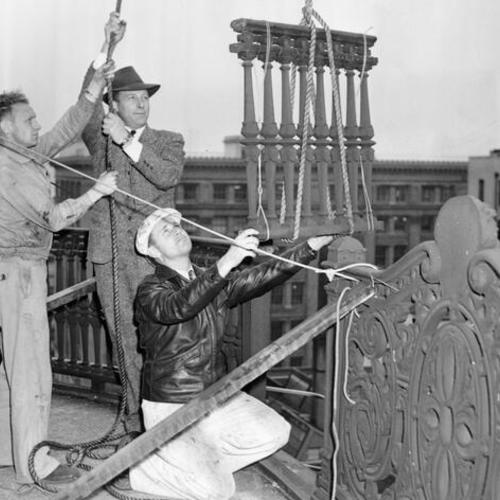 [Workmen removing the balcony and iron grill surrounding the top floor of the Palace Hotel]