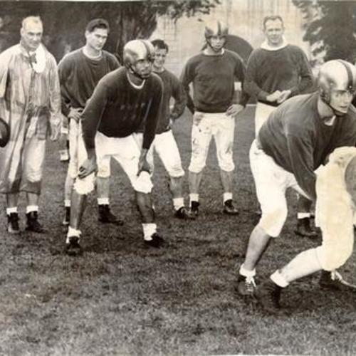 [Football players practicing for the East-West Shrine game in the rain at Kezar Stadium]