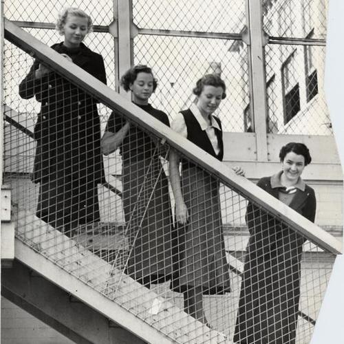 [Four students posing on an unsafe fire escape at San Francisco State Teachers' College]