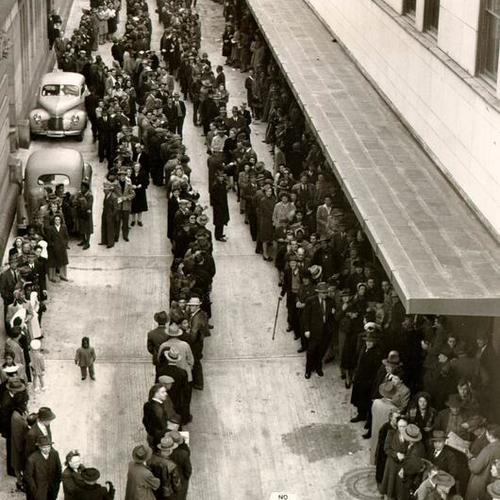 [People lining up for cigarettes in the alley behind the Appraisers Building]