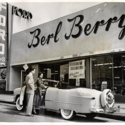 [Bud Anderson and Elizabeth McGee standing in front of Berl Berry Ford dealership]