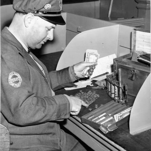 [Muni bus driver E. P. George counting money at the end of his shift]