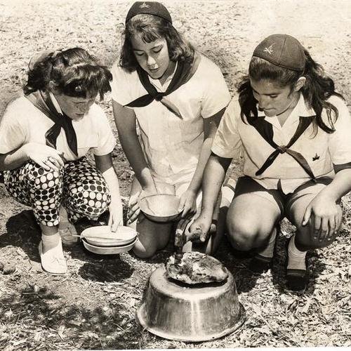 [Theresa O'Brien, Carolyn McKevitt and Joanne Maniscalco use a hammer to free a chicken baked in clay at San Francisco Camp Fire Girls camp at Balboa Park]