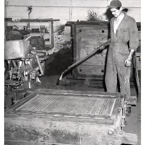 [Unidentified worker making one of the bronze plaques for the U.S.S. San Francisco memorial at Land's End in San Francisco]
