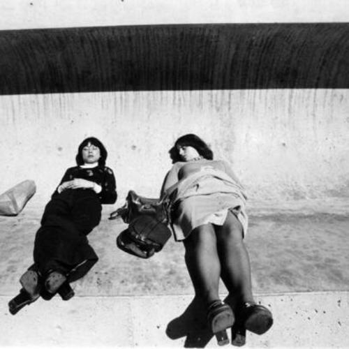 [Two women taking a nap at Embarcadero Center Plaza]