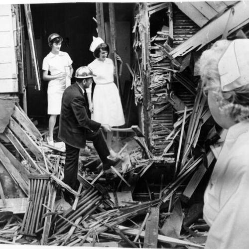 [Franklin Hospital Administrator George Monardo helping to raze a section of the old hospital while several nurses watch]