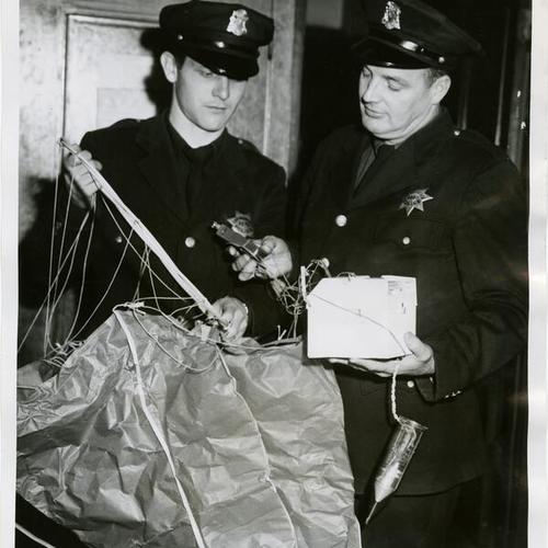 [In Richmond Police Station, Officers Lawrence Kelly and Fred Fegan examine army weather balloon that was found on a street]