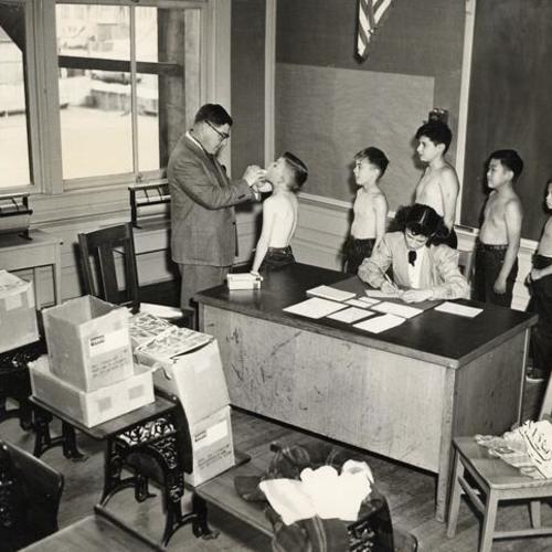 [Children receiving medical examinations in classroom at Excelsior School]