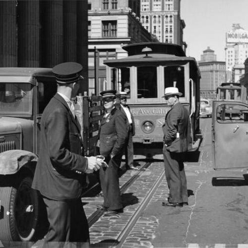 [Several men standing in front of a cable car on California street]