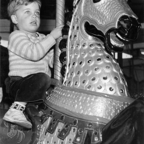[Richard Addison riding a newly painted steed on the Carousel at Children's Playground in Golden Gate Park]