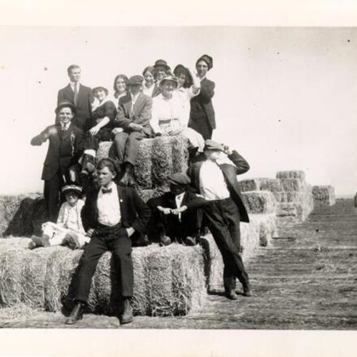 [Group of people sitting on bales of hay, Visitacion Valley]