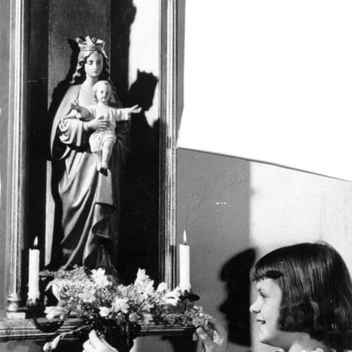 [Polly Gann, 10, places flowers before a statue from the original Episcopal Church at Steiner and Union-sts.]