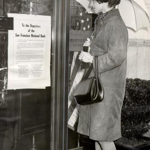 [Gerry George looking at instructions posted on the bank window of the San Francisco National bank]