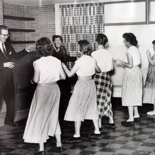 [Dance instructors Roy Harding and Sophie Griswold teaching a class of girls at the Youth Guidance Center a new dance step]