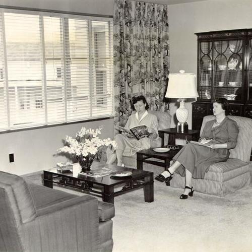 [Eileen Rogers and Corabell Carlisle sitting in a furnished apartment in Parkmerced]